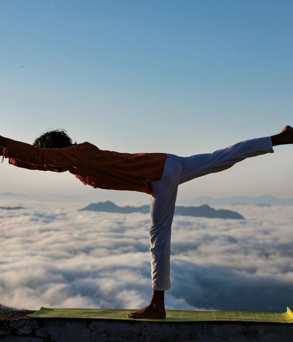 Man in a warrior yoga pose against a dark, minimalist background.